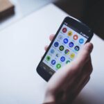 Une personne tient un smartphone affichant des icônes d'applications mobiles.