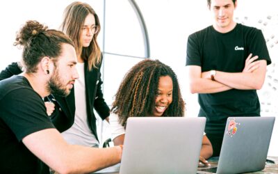 A diverse group of young professionals collaborating enthusiastically in a bright, modern workspace.
