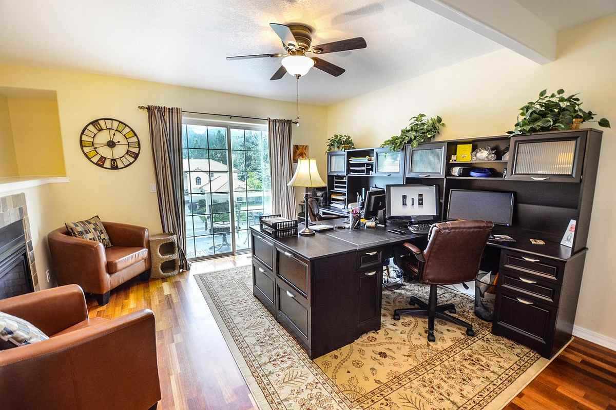 Un bureau moderne avec chaise ordinateur étagères tapis et vue sur terrasse