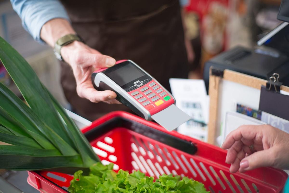 Paiement au terminal de caisse avec panier de courses et légumes Paiement au terminal de caisse avec panier de courses et légumes