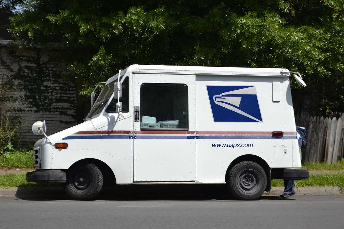 Camion de livraison USPS blanc garé sur rue conducteur à côté