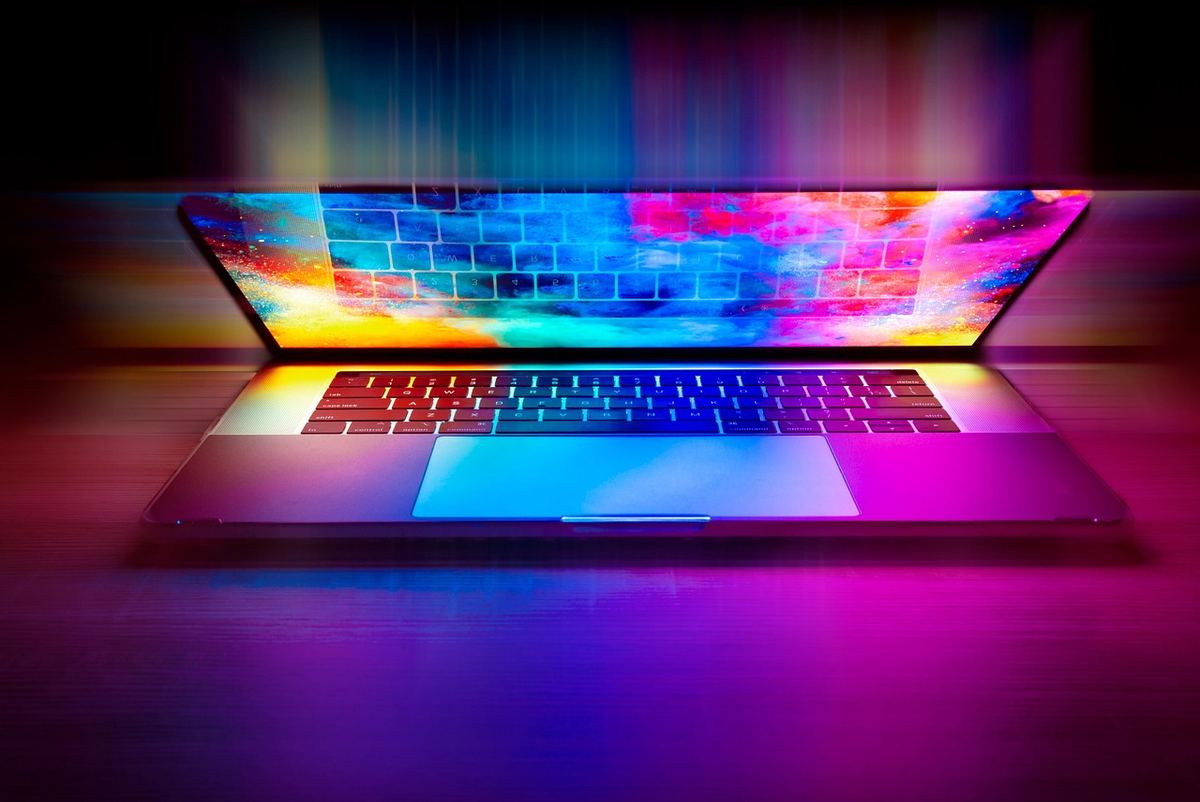 Un ordinateur portable ouvert projette des couleurs vives sur le clavier et le pavé