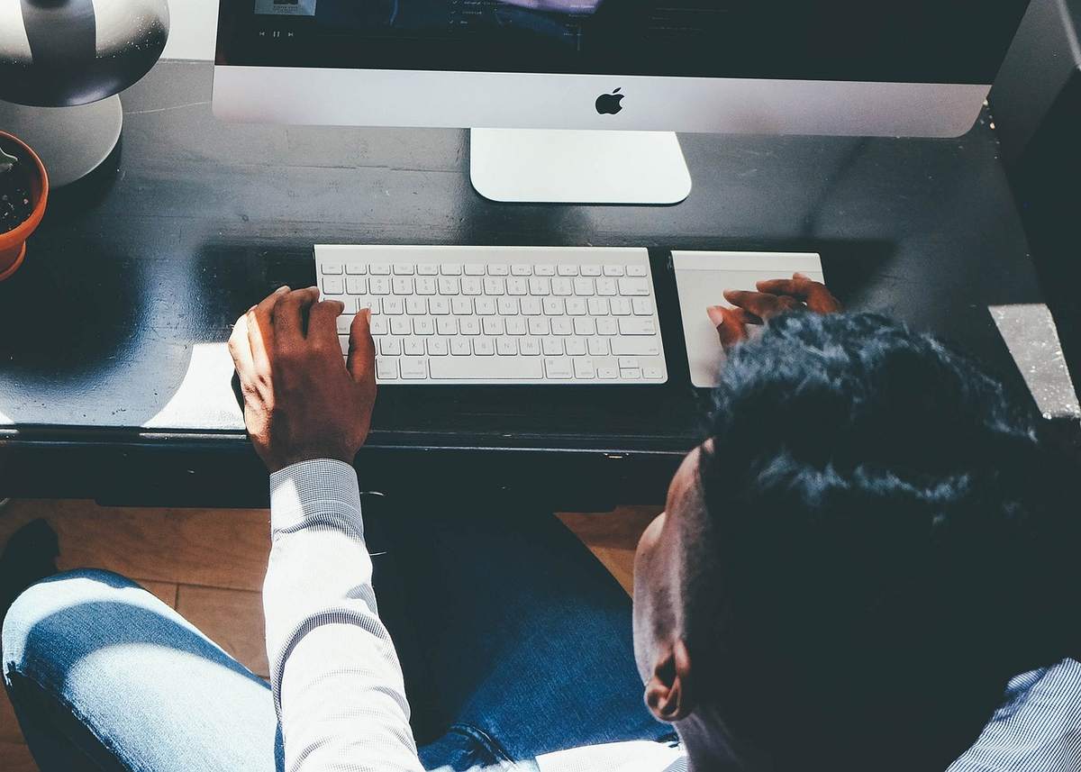 Un homme travaille sur un ordinateur de bureau avec clavier et souris