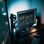 Un poste de travail avec écran clavier souris et micro dans une pièce sombre