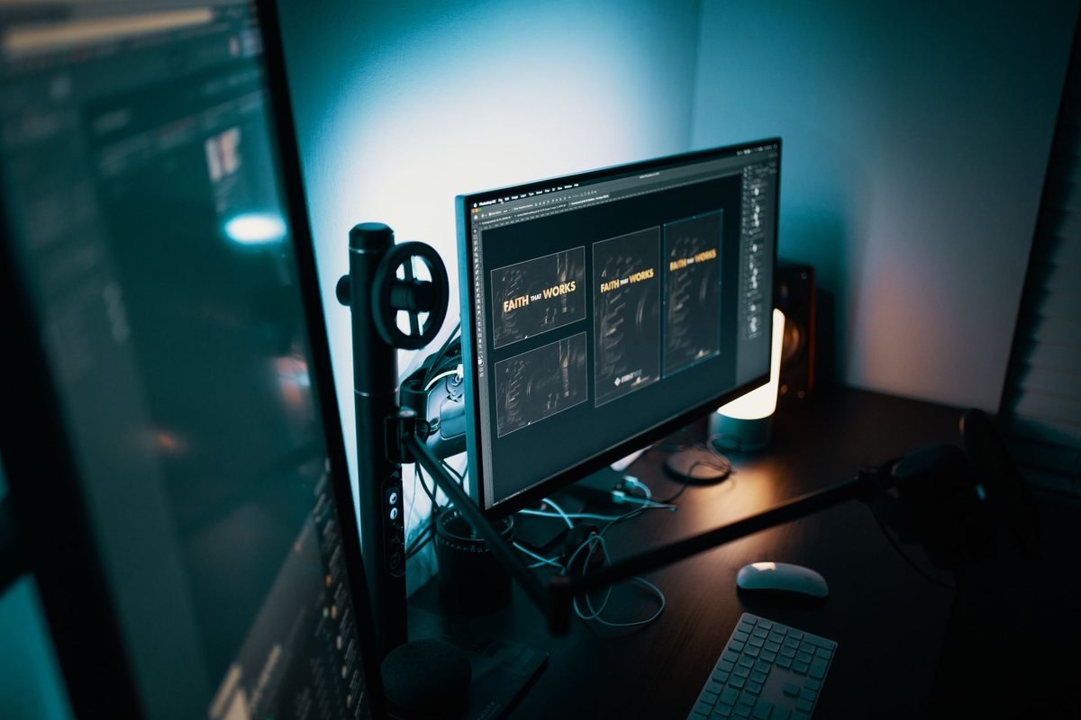 Un poste de travail avec écran clavier souris et micro dans une pièce sombre