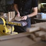 Homme ponçant du bois sur une machine dans un atelier de menuiserie