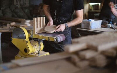 Homme ponçant du bois sur une machine dans un atelier de menuiserie
