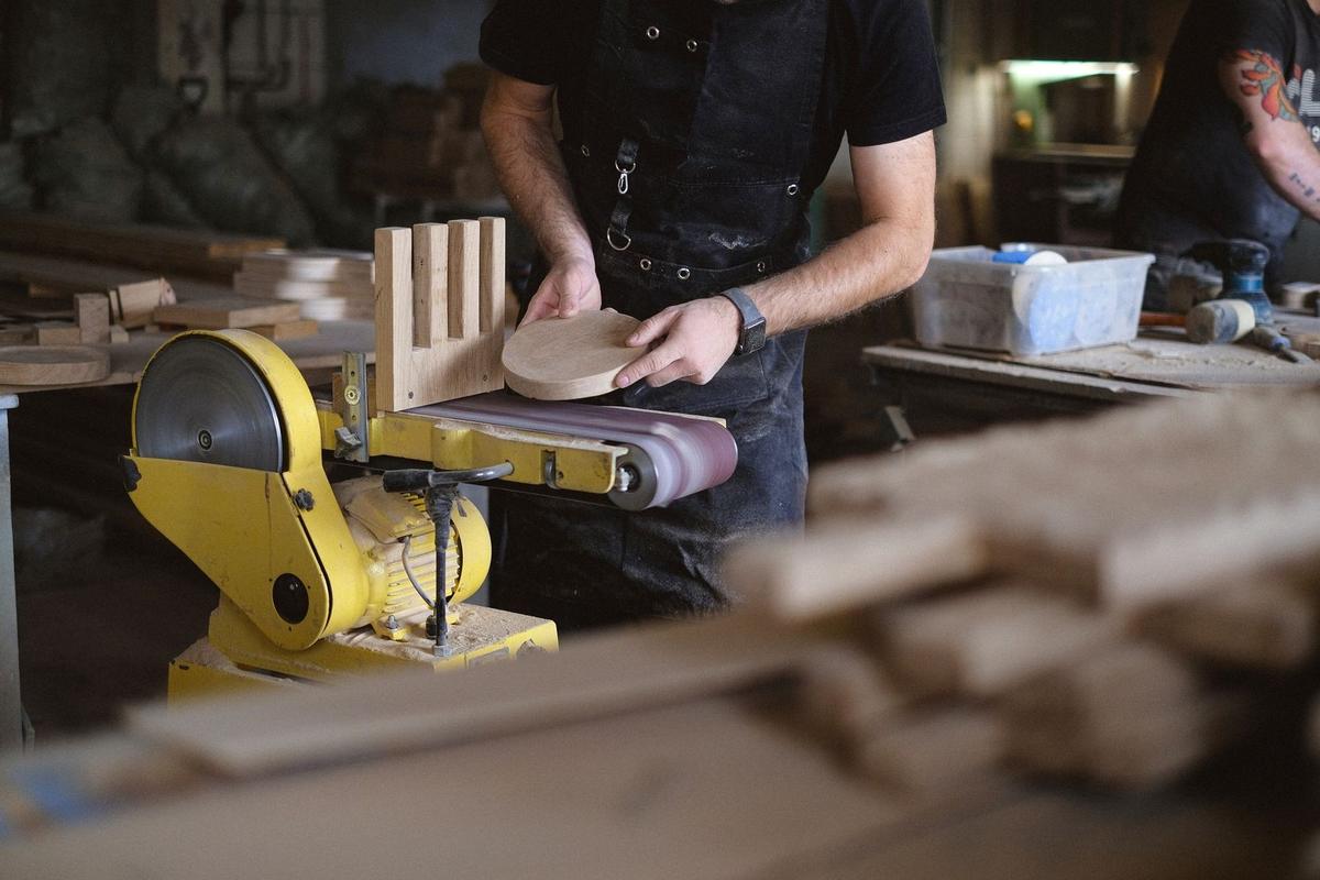Homme ponçant du bois sur une machine dans un atelier de menuiserie
