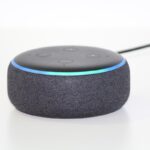 Un petit haut-parleur intelligent noir avec anneau lumineux bleu