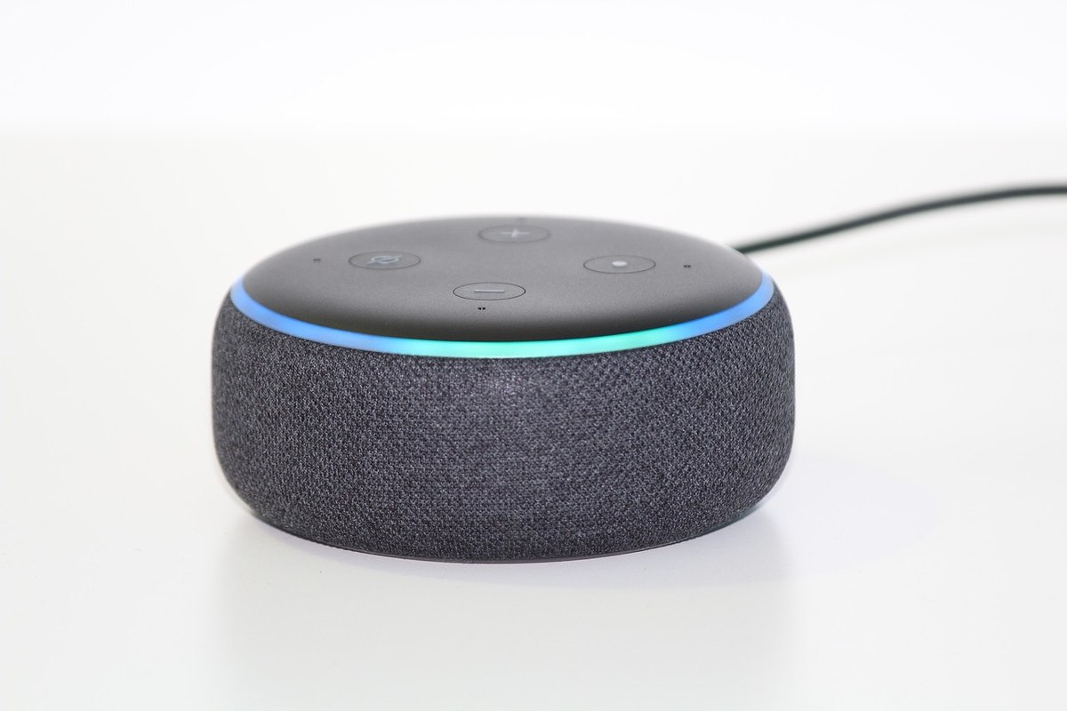 Un petit haut-parleur intelligent noir avec anneau lumineux bleu